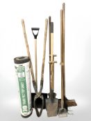 A group of garden tools and a roll of felt roofing.