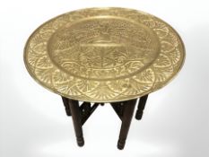 An embossed brass bobbin turned occasional table with Egyptian themed top, diameter 56 cm.