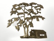 A cast brass plaque depicting a cabin beneath a tree,