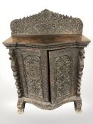 A 19th century Anglo-Indian heavily carved padouk bowfront double door side cabinet,
