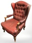 A beech framed Chesterfield-style wingback armchair in oxblood buttoned leather.
