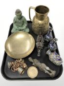 An Islamic embossed brass jug, patinated metal figure of Buddha, brass bells,