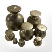 Eight graduated brass weights, ranging from two ounces to fourteen pounds, tallest 12 cm.