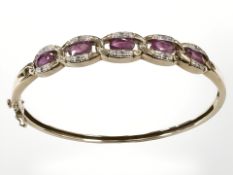 A 9ct yellow gold diamond and ruby bangle, 58 mm x 52 mm internal diameter, 12.2g.