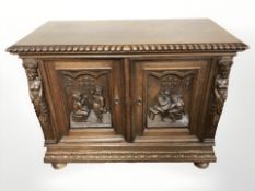 A 20th century continental heavily carved oak double door low cabinet on bun feet,
