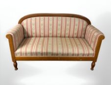 An early 20th century continental walnut salon settee in striped floral upholstery,