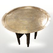A Middle Eastern bobbin turned folding occasional table with brass top depicting Egyptian scenes,