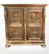 An early 20th century heavily carved oak cabinet on bun feet,