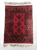 A small Afghan rug on red ground,