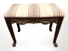 An early 20th century carved beech piano stool on paw feet,