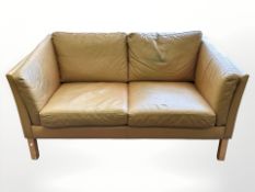 A late 20th century Danish faded tan leather two seater settee,