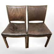 A pair of chairs in brass studded brown vinyl