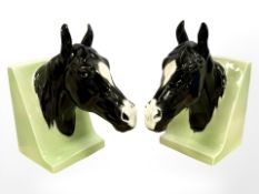 A pair of glazed bookends, each modelled as a head of a black horse,