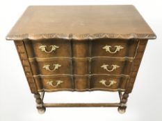 A 20th century carved oak serpentine front three drawer chest,