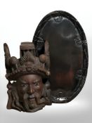 An oriental carved hardwood wall mask with inset glass eyes, and an oval tray carved with koi fish,