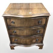 A reproduction mahogany serpentine-front three drawer chest,