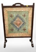 A mahogany fire screen with applied stamp collage to front and back, height 84 cm.