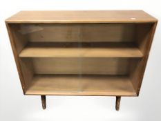 A 20th century teak sliding glass door low bookcase, designed by Herbet E.