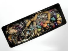 A tin of assorted costume bead necklaces, bangles, bracelets, etc.