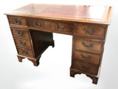 A reproduction mahogany nine drawer twin pedestal desk with leather inset top,