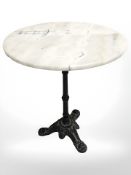 A cast iron tripod table with marble top,