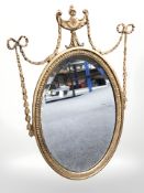 An early 20th century gilt gesso oval mirror, in the Adams style, 74 cm x 46 cm.