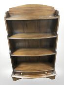 A reproduction mahogany bowfront open bookcase, 67 cm x 25 cm x 110 cm.
