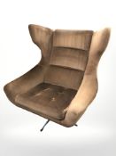 A 1970's wing back swivel lounge chair on chrome support in brown upholstery,