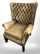 A 20th century studded tan leather chesterfield wingback armchair, width 82 cm.