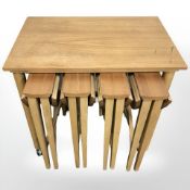 A teak occasional table on casters with four folding stowaway tables beneath, width 62 cm.
