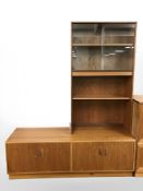 A G Plan teak low sideboard, fitted cupboards with sliding glass door bookcase above,