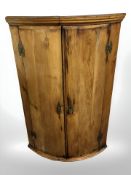 A George III pine bow front hanging corner cabinet, height 103 cm.