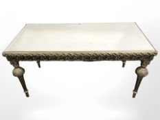 A gilt plaster coffee table with mirrored top, length 94 cm.