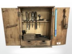 A wall mounted tool cabinet containing carpentry chisels, other tools etc,