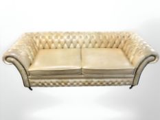 A contemporary studded tan leather three seater chesterfield settee, 222 cm x 90 cm x 76 cm.
