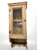 A glazed pine single door wall cabinet,