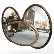 Two Edwardian mahogany bevelled oval mirrors and a further oak mirror, width 82 cm.