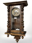 A late Victorian mahogany wall clock with enameled dial, length 68 cm, with key and pendulum.