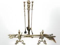 A pair of brass fire dogs and two companion sets.