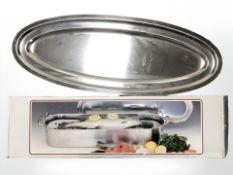 A stainless steel fish kettle in box and a further oval serving platter, width 80 cm.