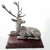 A silver plated figure of a recumbent stag on wooden plinth, height 16 cm.