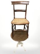 A cast iron table with circular pine top and a cane work seated chair