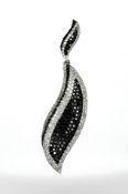 An 18ct white gold leaf pendant, set with 157 black diamonds and 169 white diamonds,