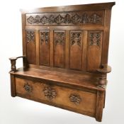 An Arts and Crafts carved oak panel back storage settle, 192 cm x 43 cm x 178 cm.
