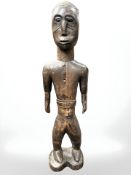 An African carved wooden statue of a man wearing a buttoned shirt, height 67 cm.