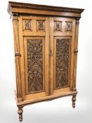 An Arts and Crafts heavily carved oak double door wardrobe, 124 cm x 54 cm x 187 cm.