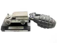 An inert hand grenade and a die cast metal military land rover on plinth, width 13 cm.