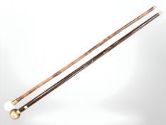 A walking cane with railway regulator timepiece pommel and a further cane with carved resin pommel,
