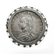 A silver brooch with Victoria 1887 half crown.