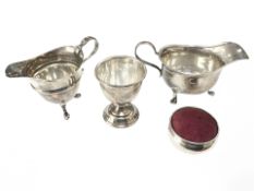 Two silver sauce boats, an egg cup, and a pin cushion, tallest 6cm.